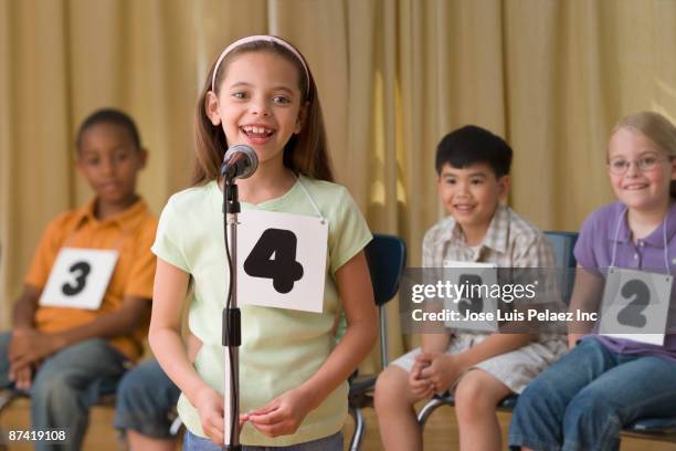 hispanic girl giving answer in spelling bee - microphone mouth stock-fotos und bilder