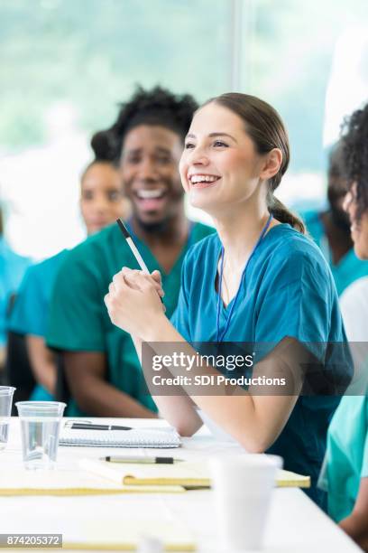 smiling attentive healthcare professional during medical seminar - nurse education stock pictures, royalty-free photos & images