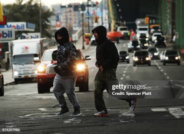 Men run in front of cars on a busy road on November 14, 2017 in New York City. According to a new report by the International Energy Agency, global...