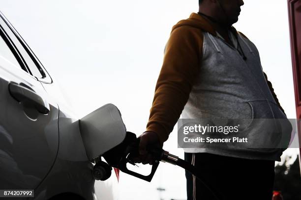 Man fills his car up with gas at a station on November 14, 2017 in New York City. According to a new report by the International Energy Agency,...