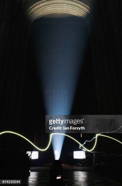 Lighting engineer wearing a head torch walks through the picture as the inside of the historic Durham Cathedral is illuminated by a light...