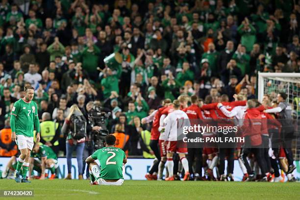 Republic of Ireland players react to their defeat as denmark players celebrate on the pitch after the FIFA World Cup 2018 qualifying football match,...