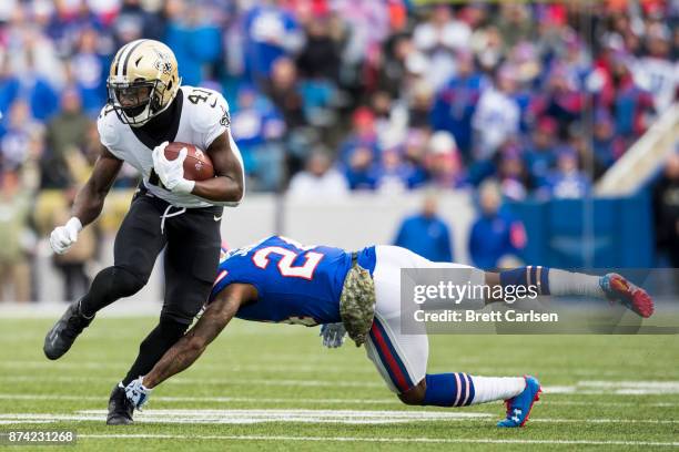 Alvin Kamara of the New Orleans Saints carries the ball as Leonard Johnson of the Buffalo Bills dives attempting to tackle during the first quarter...
