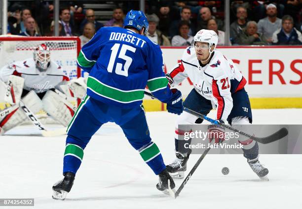 Derek Dorsett of the Vancouver Canucks and Madison Bowey of the Washington Capitals look at a loose puck during their NHL game at Rogers Arena...