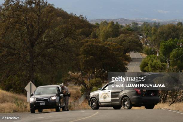 Highway Patrol officer speaks to a woman while blocking off a road to traffic after a shooting on November 14 in Rancho Tehama, California. Four...