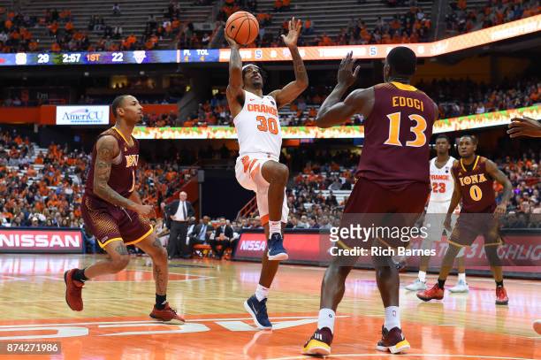 Geno Thorpe of the Syracuse Orange shoots the ball between Zach Lewis and TK Edogi of the Iona Gaels during the first half at the Carrier Dome on...
