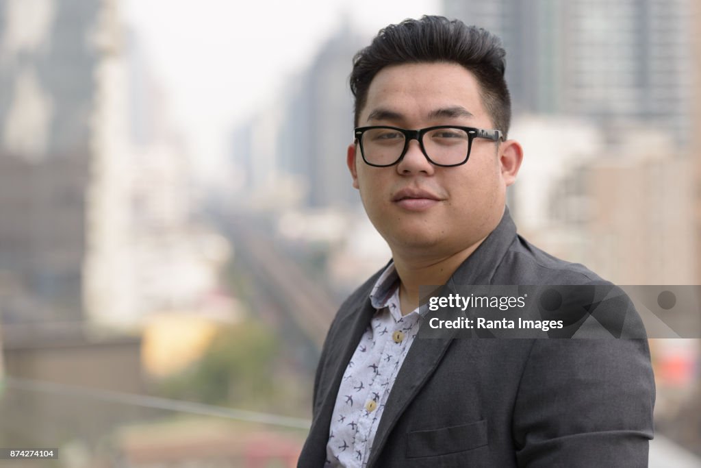 Junge hübsche asiatische Geschäftsmann genießt das Leben in der Stadt von Bangkok, Thailand