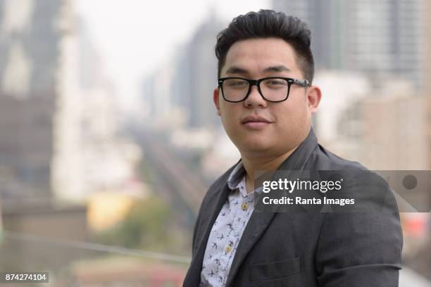 jonge knappe aziatische zakenman genieten van het leven in de stad van bangkok, thailand - bril met hoornen montuur stockfoto's en -beelden