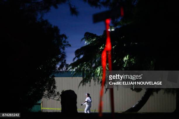 Woman wearing a white protective suit is seen on the Rancho Tehama Elementary school grounds after a shooting on November 14 in Rancho Tehama,...