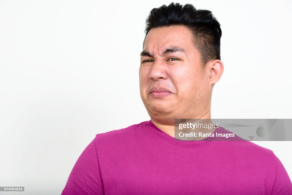 Giovane bel uomo asiatico che indossa una camicia viola su sfondo bianco