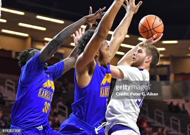 Forward Dean Wade of the Kansas State Wildcats drives to the basket against defenders Jordan Giles and Aleer Leek of the Missouri-Kansas City...