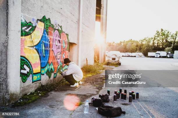 young man doing graffiti - graffiti artist stock pictures, royalty-free photos & images