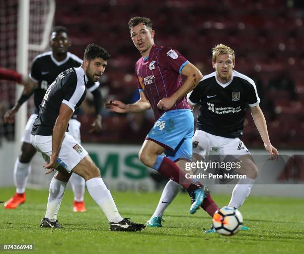 Tom Hopper of Scunthorpe United plays the ball watched by Yaser Kasim of Northampton Town during the Emirates FA Cup First Round Replay match between...