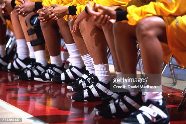 women's basketball team on bench, low angle view - basketball uniform stock-fotos und bilder