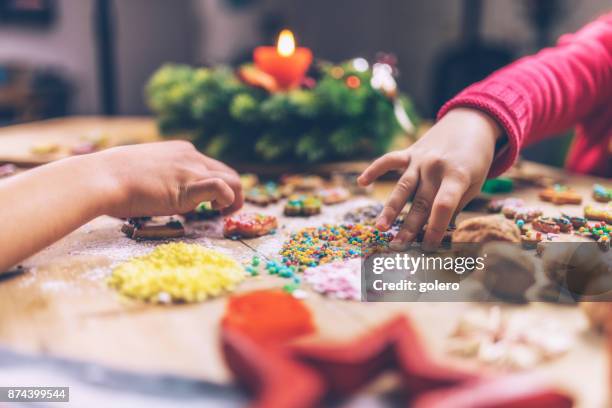 kids hands decorating christmas cookies together - kids advent stock pictures, royalty-free photos & images