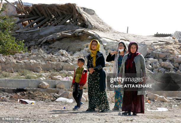 Picture taken on November 15, 2017 shows Iranians walking past the rubble of buildings in Kouik village near to Sarpol-e Zahab, two days after a...