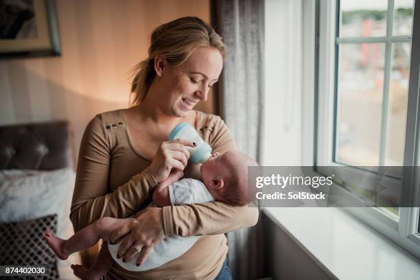 moeder haar zoon baby voeding - baby bottle stockfoto's en -beelden