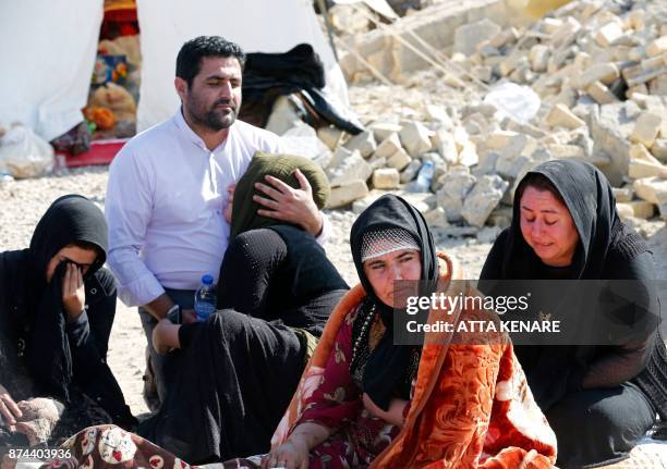 Picture taken on November 15, 2017 shows Iranians mourning next to the rubble of their home in Kouik village near to Sarpol-e Zahab, two days after a...