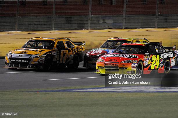 Jeff Gordon driver of the DuPont Chevrolet races for the lead with Matt Kenseth driver of the DeWalt Ford and Kyle Busch driver of the M&M's Toyota...