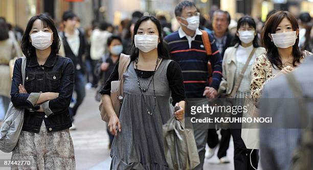 Pedestrians wearing masks walk along a street in downtown Kobe, Hyogo prefecture, in western Japan on May 17, 2009. Japan said on May 17 that nine...