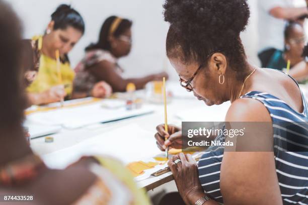 group of brazilian women painting textiles in work room of social project - craft product stock pictures, royalty-free photos & images