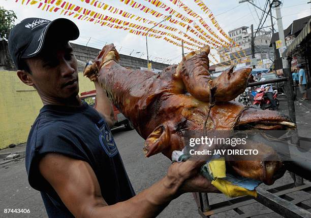 Worker delivers roasted pork which will be paraded through the La Loma district of Manila on May 17 as part of an annual festival. Roast pigs, called...