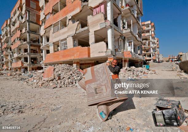 An Iranian carries away a rug from the damaged buildings in the town of Sarpol-e Zahab in the western Kermanshah province near the border with Iraq,...