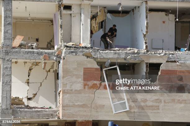 Iranians lower a salvaged door frame through the gap where a wall once stood in a building's facade after quake damage in the town of Sarpol-e Zahab...