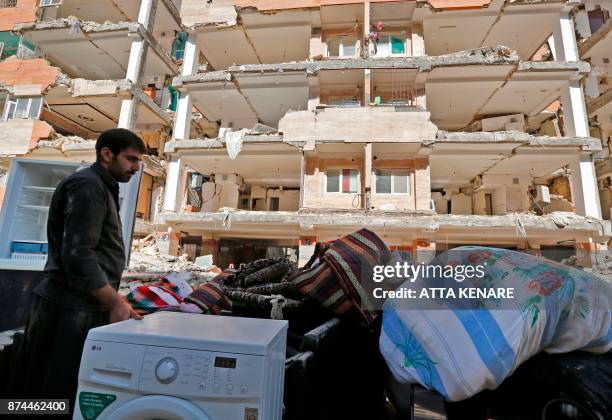 Iranians salvage their furniture and household appliances as they bring them outside the damaged buildings in the town of Sarpol-e Zahab in the...