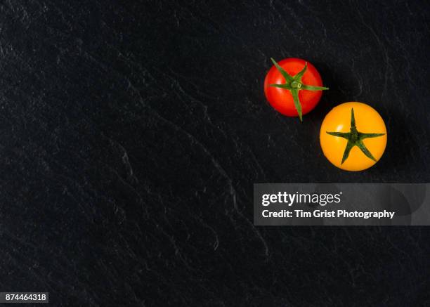 red and yellow tomatoes on slate surface - schieferplatten stock-fotos und bilder