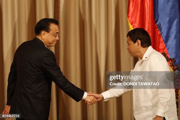 Philippines' President Rodrigo Duterte shakes hands with China's Premier Li Keqiang during Li's one-day state visit at the Malacanang Palace in...