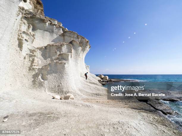 rocky coast of the cabo de gata with formations of volcanic rock of white color with a woman traveler between the rocks. cabo de gata - nijar natural park, cala del plomo, beach, biosphere reserve, almeria,  andalusia, spain - costa rochosa - fotografias e filmes do acervo