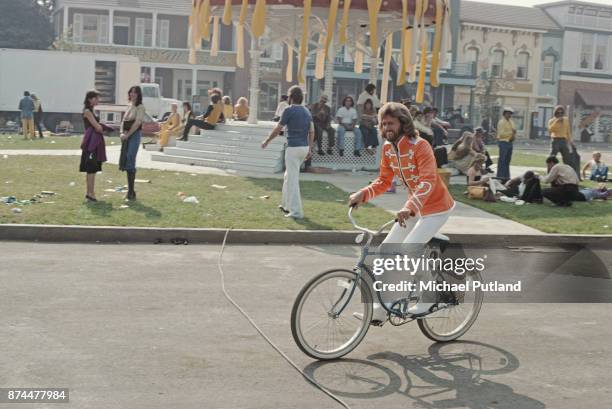 British singer Barry Gibb of pop group The Bee Gees riding a bicycle on the set of 'Sgt Pepper's Lonely Hearts Club Band' musical comedy film,...