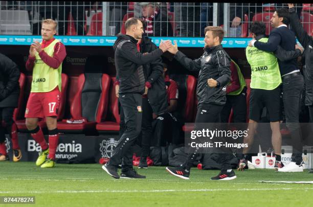 Head coach Heiko Herrlich of Leverkusen shakes his hand with co-coach Nico Schneck during the Bundesliga match between Bayer 04 Leverkusen and 1. FC...