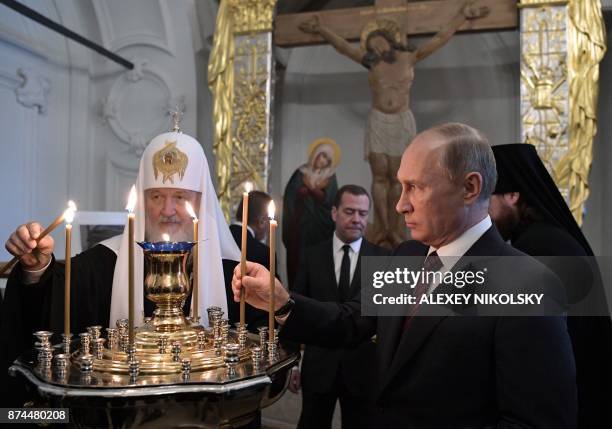 Russian President Vladimir Putin , accompanied by Patriarch of Russia Kirill and Prime Minister Dmitry Medvedev, places a candle as he visits the New...