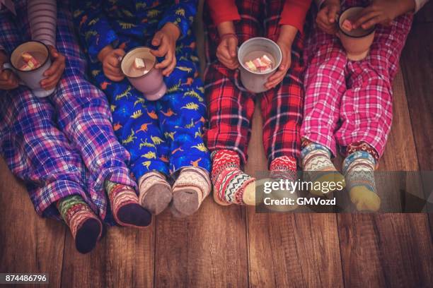 schattige kleine kinderen in pyjama en kerst sokken drinken warme chocolademelk met marshmallows voor kerstmis - girls in socks stockfoto's en -beelden