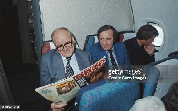England manager Ron Greenwood reading a copy of Onze Magazine during a flight with coaches Billy Taylor and Geoff Hurst circa March 1980.