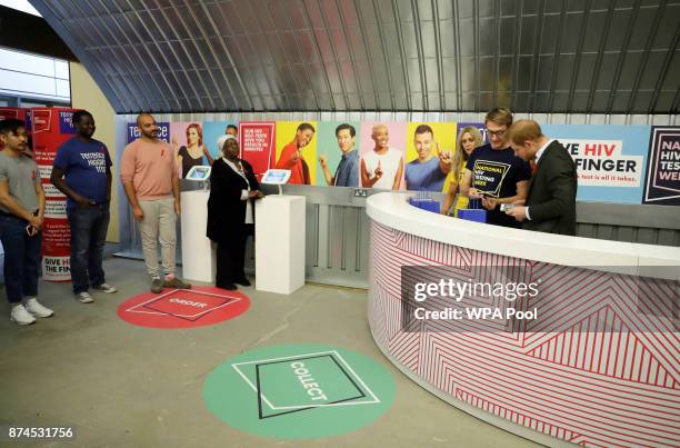 Local residents, who volunteered, wait in line as Britain's Prince Harry prepares to give them HIV self-test kits during his visit to the opening of...