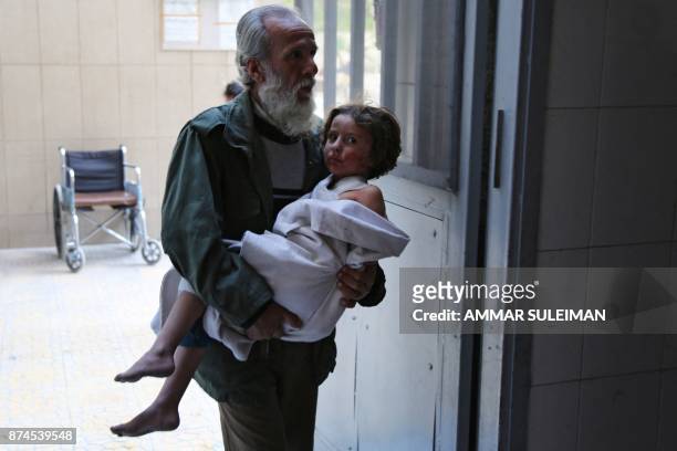 Man carries a wounded child into the emergency ward of a hospital in the Eastern Ghouta town of Kafr Batna on the outskirts of Damascus, following...
