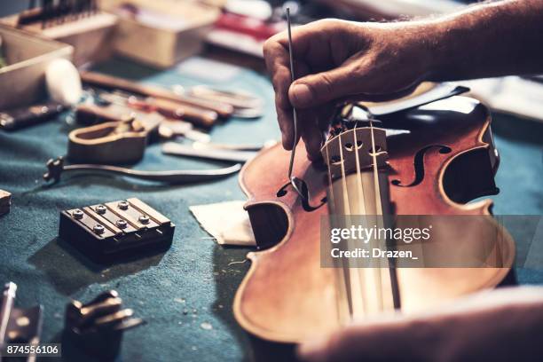 old school-reparateur op zoek naar de ziel van de viool - instrumentenmaker stockfoto's en -beelden