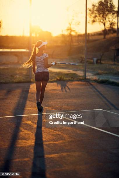 teenage girl playing tennis on sunset - bouncing tennis ball stock pictures, royalty-free photos & images