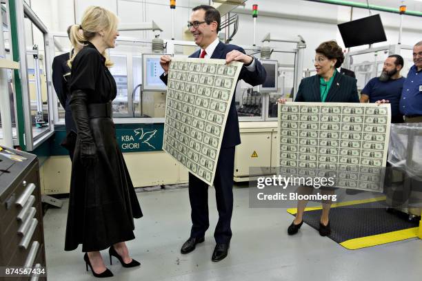 Steven Mnuchin, U.S. Treasury secretary, center, displays a 2017 50 subject uncut sheet of $1 dollar notes bearing Mnuchin's name for his wife Louise...