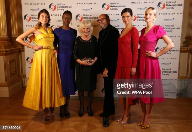 Camilla, Duchess of Cornwall and Bruce Oldfield pose for a photograph with models wearing his dress designs the Bruce Oldfield Fashion Show at...