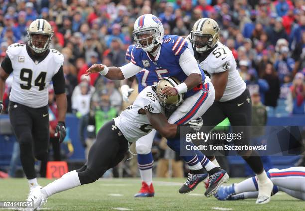 Tyrod Taylor of the Buffalo Bills is hit by Rafael Bush of the New Orleans Saints as he throws a pass during NFL game action at New Era Field on...