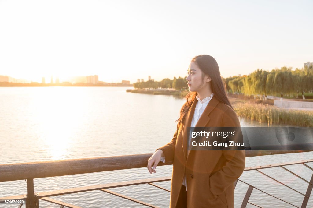 Thoughtful woman standing on bridge during twilight
