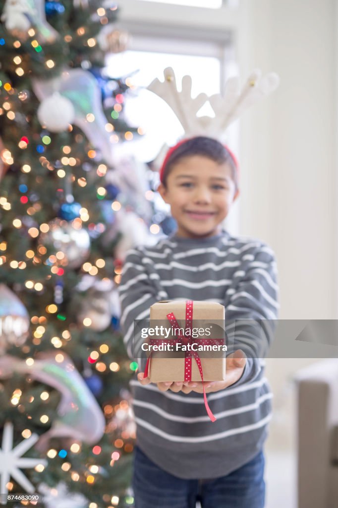 A young boy delightedly holds open a wrapped present