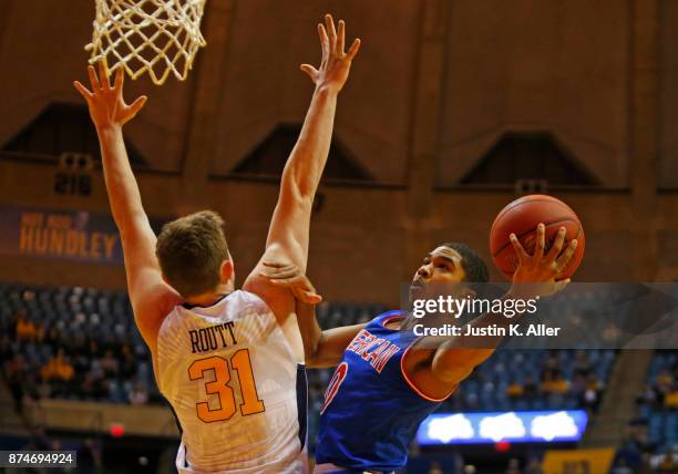 Sa'eed Nelson of the American University Eagles drives to the basket against Logan Routt of the West Virginia Mountaineers at the WVU Coliseum on...