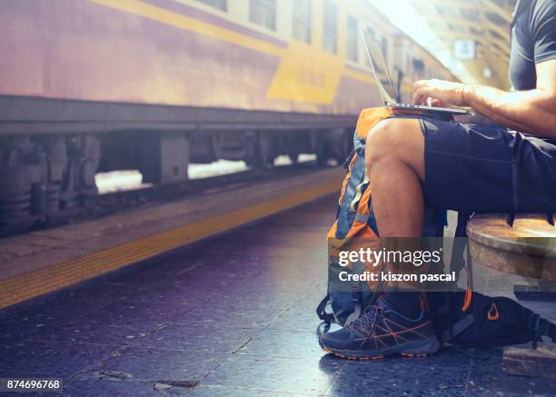 digital nomad backpacker working on computer while waiting for train . - pessoas nómadas imagens e fotografias de stock