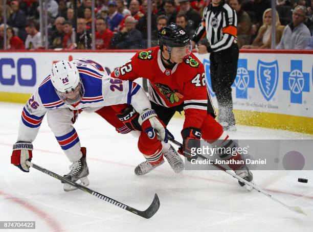Jimmy Vesey of the New York Rangers and Gustav Forsling of the Chicago Blackhawks battle for position on the puck at the United Center on November...