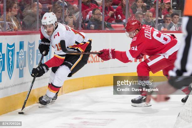 Matthew Tkachuk of the Calgary Flames skates with the puck behind the net followed by Xavier Ouellet of the Detroit Red Wings during an NHL game at...